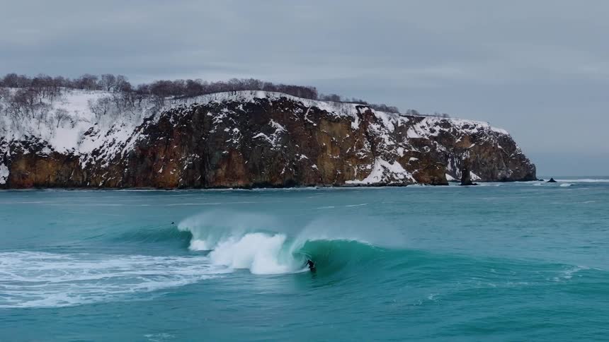 Surfer rides a wave on an overcast winter day