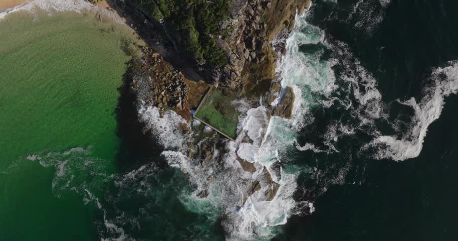 Aerial view of the sea crashing against the rocky coastline