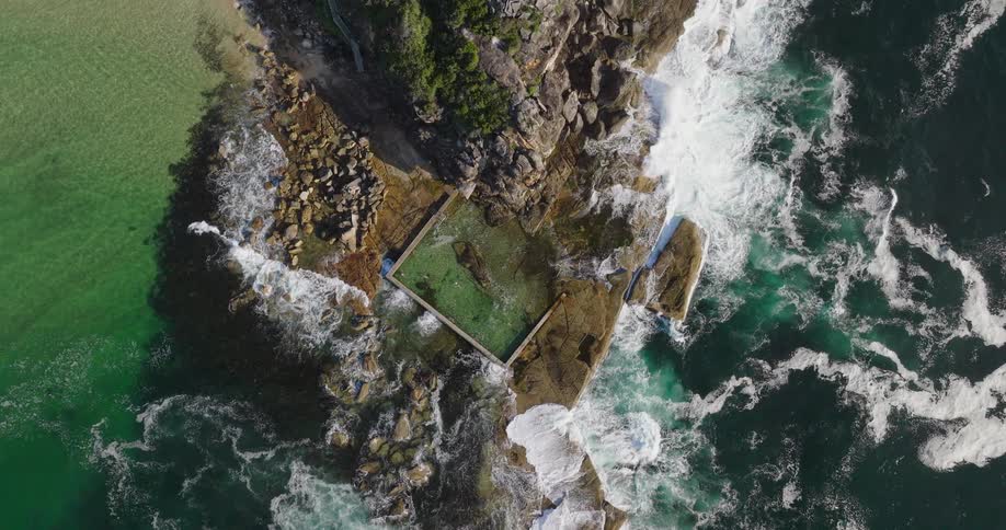 Aerial view of a natural pool on a rocky coast surrounded by the sea