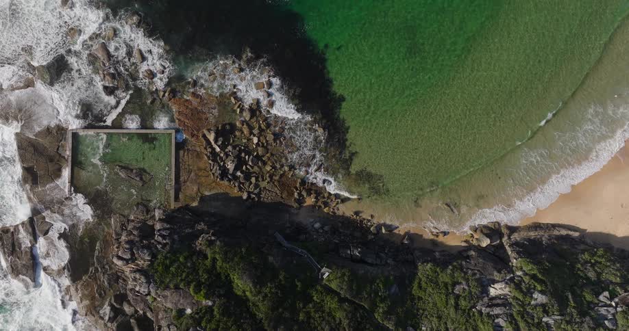 Ocean waves crash against rocks near the mountain
