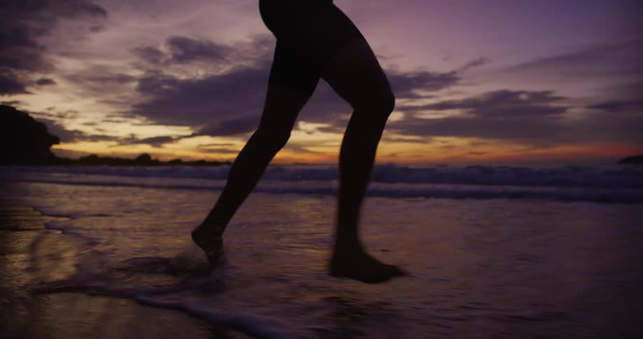 Person is jogging on the coast of the beach while the sun is setting