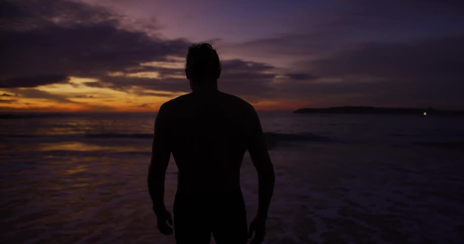 Silhouette of a man walking on the beach at sunset