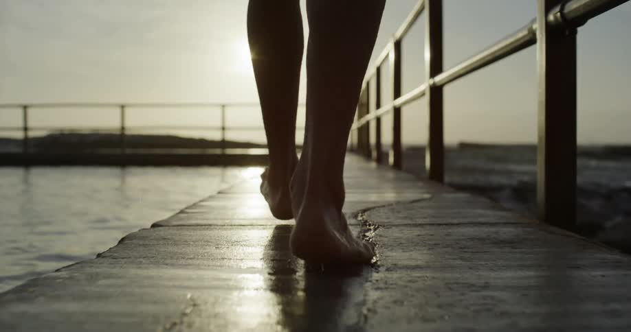 A person is walking by a pool near the beach