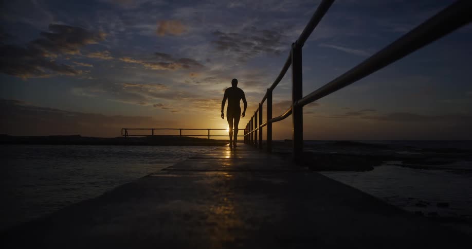 A man is walking on a platform by the ocean