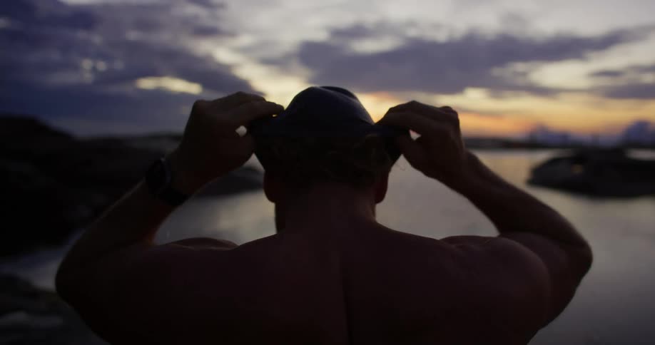 Man from behind putting on swimming cap