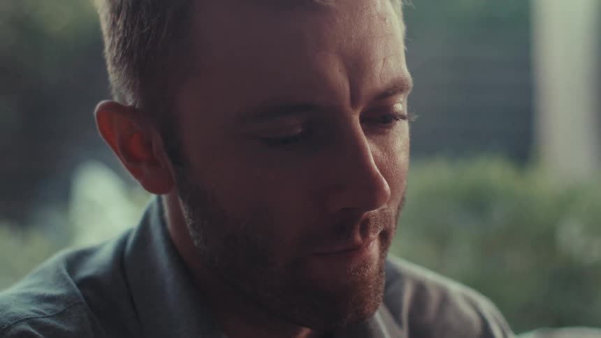 A man is sitting indoors near a window in a city