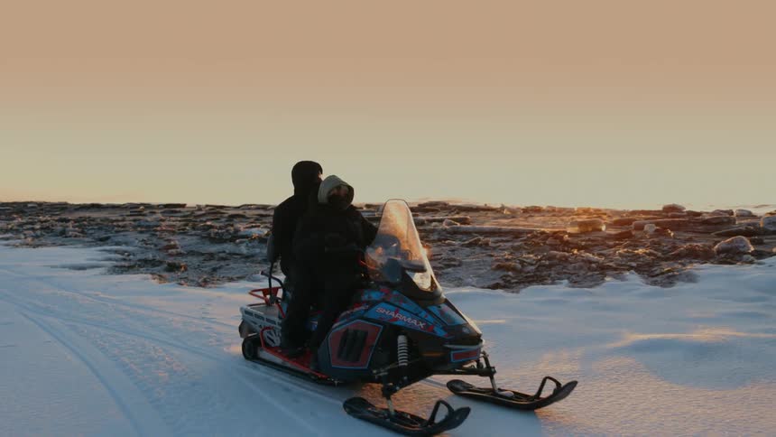 Two people riding a snowmobile