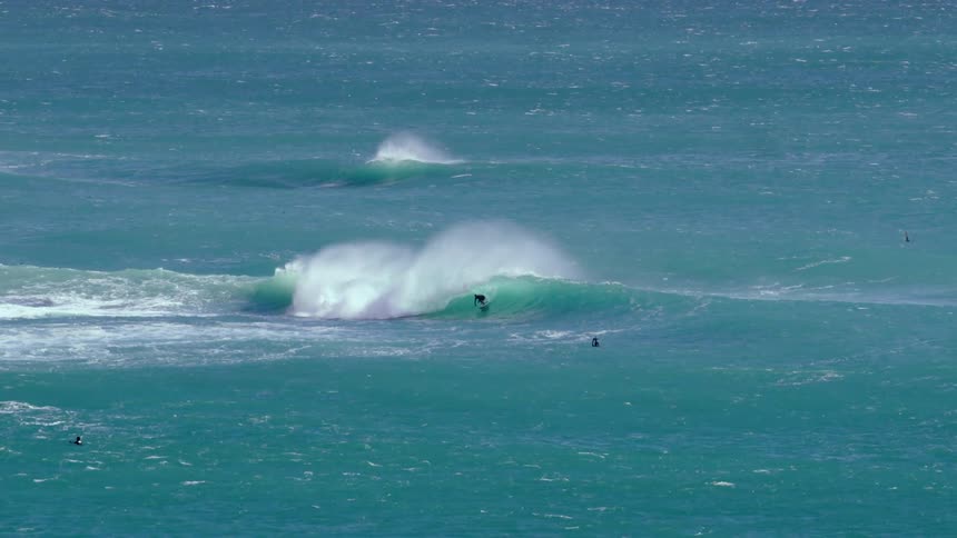 Surfer surfing a wave in the ocean in the distance