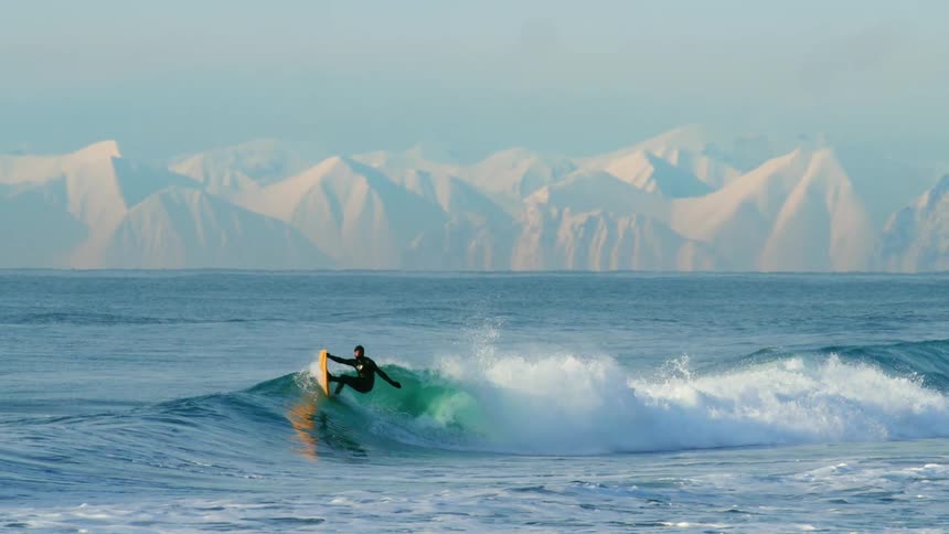 A surfer in a black wetsuit riding a wave that is breaking next to him