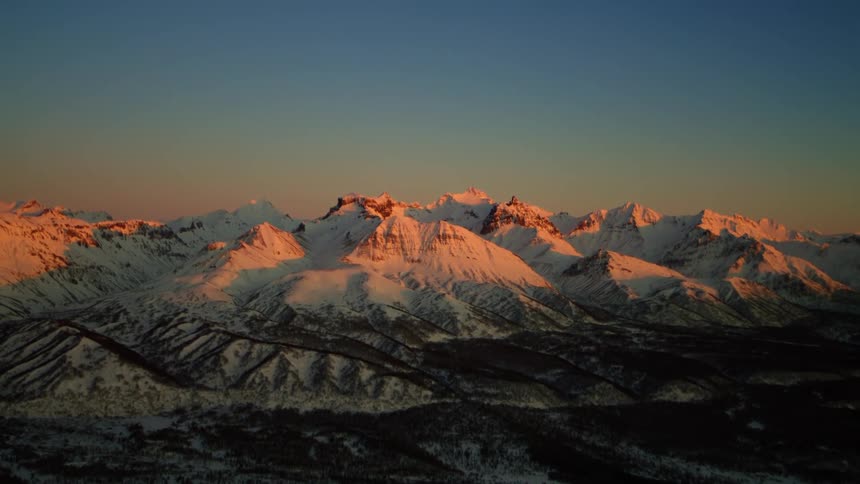 The sun is setting in the horizon above the mountaintops