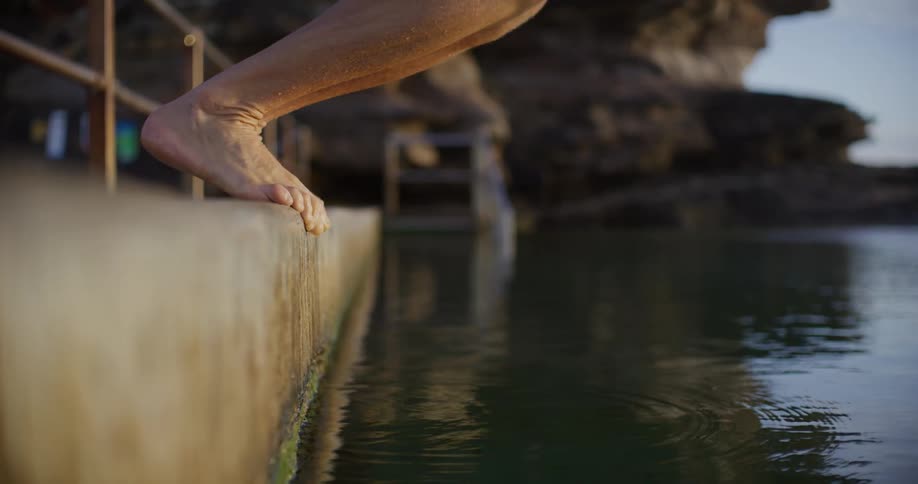 Person is diving off a dock into a body of water in spring