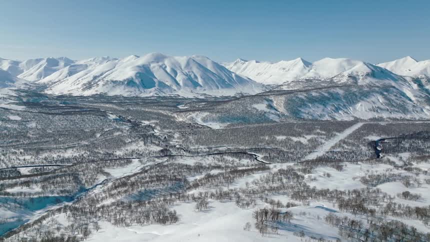 Aerial view of a snowy mountain valley with river trails