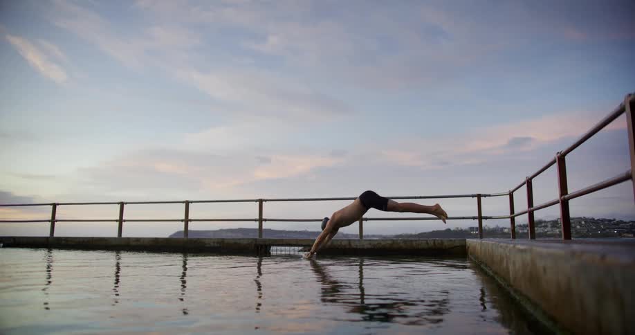 Man standing on a dock dives into the water