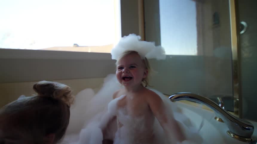 Two little girls taking a bath in a bathtub with bubbles