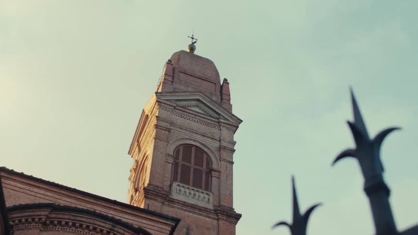 An ornate church steeple framed by wrought iron gates