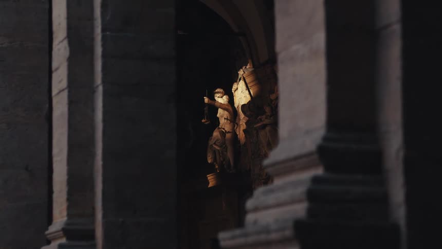 A statue is in front of the stone building