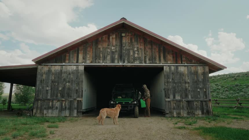 Person with a dog walking towards a farm vehicle and filling up with fuel