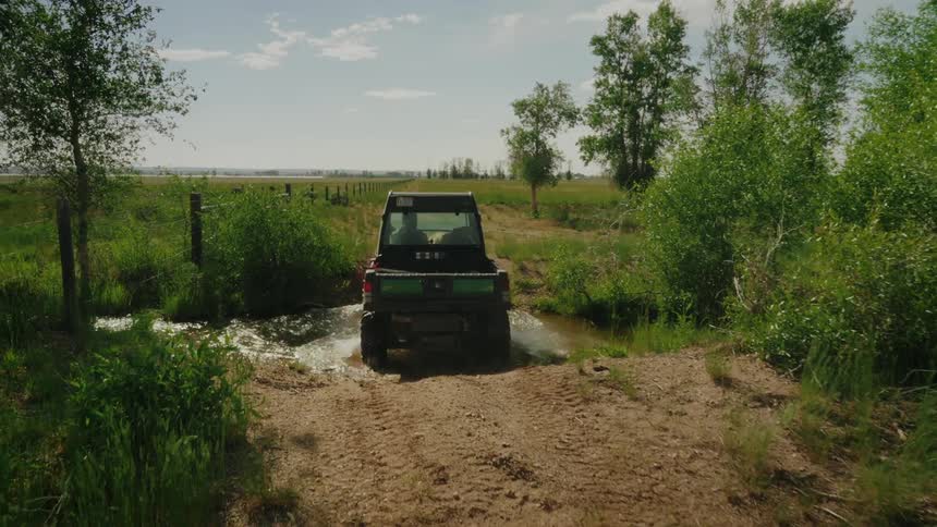Person and a dog inside a small offroad farm truck crossing a lake
