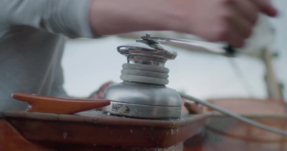 A persons hand turning a tool that is pulling a rope