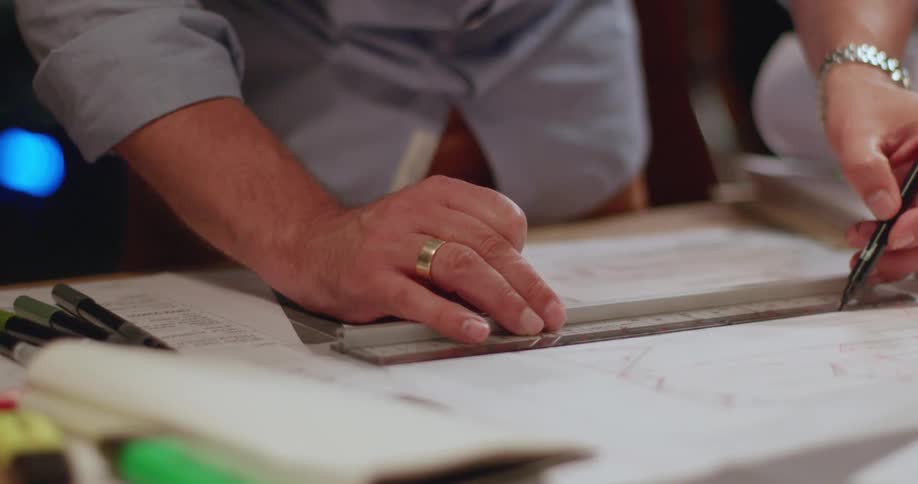 An architect uses a pen and ruler to draw lines