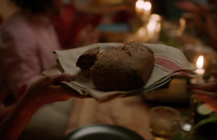 People sitting at a table at night and serving themselves with bread