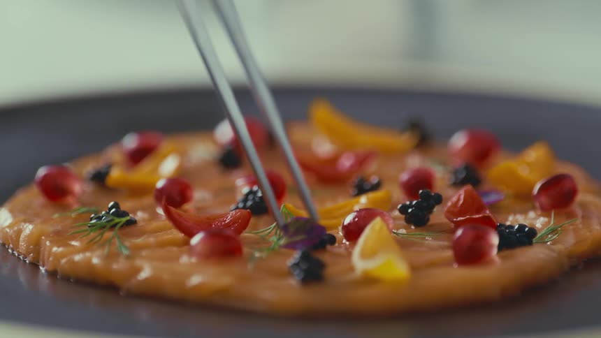 A plate of salmon tartare is garnished with pomegranate seeds caviar and other colorful ingredients