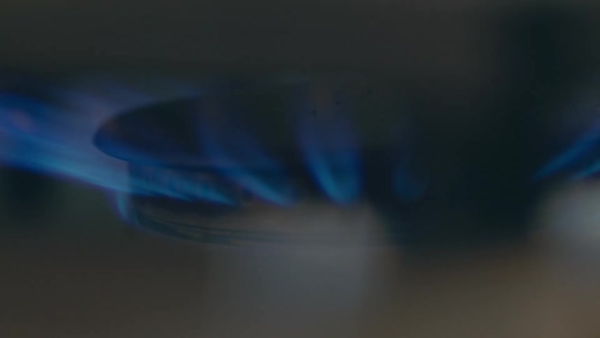Gas burner lights with orange and blue flames before burning predominately blue