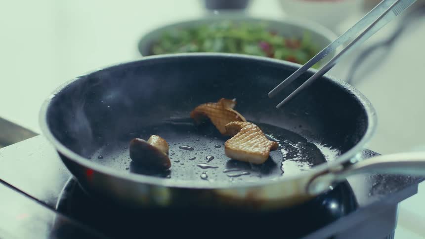 Closeup of a woman sauteing mushrooms in a pan
