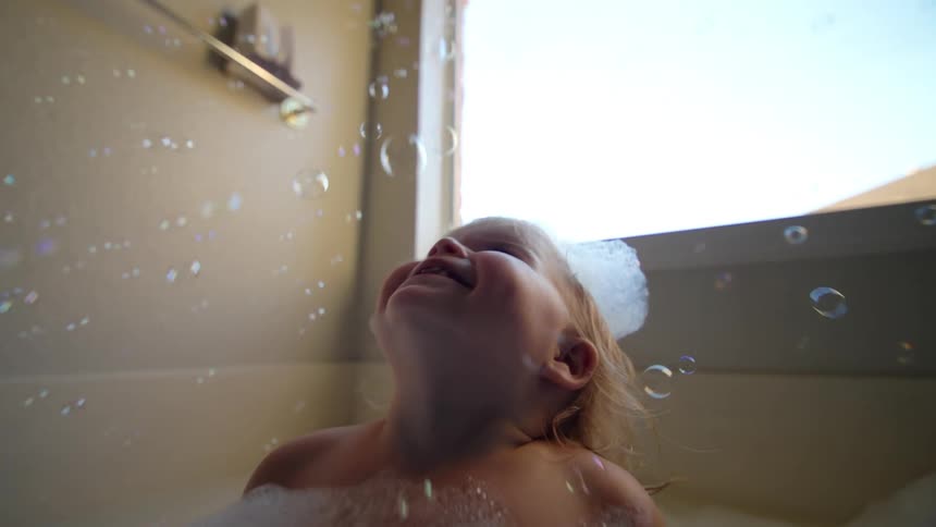 Two little girls in bathtub with soap bubbles and foam