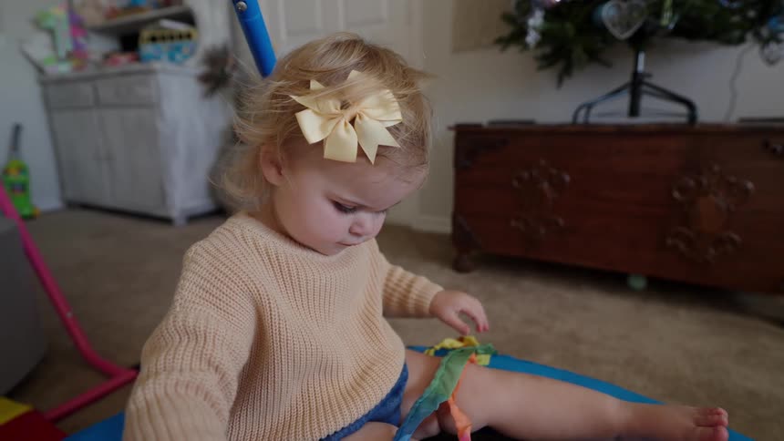 A girl playing with a colorful ribbon wand in her bedroom