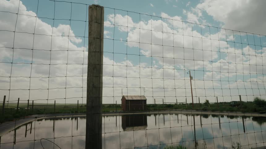Water tank on a fence with a wooden house in the background