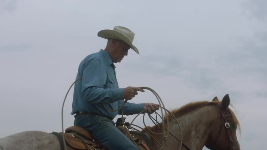 Cowboy riding a horse wearing a typical hat and holding a lasso