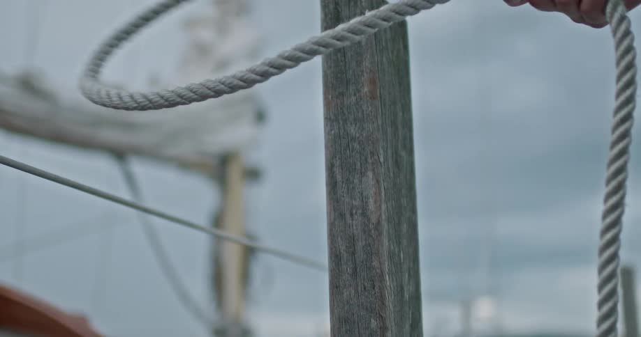 Hand taking a rope off a wooden support and putting it back on