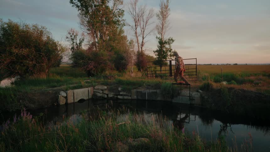 Man walking on a ranch and inspecting an irrigation gate