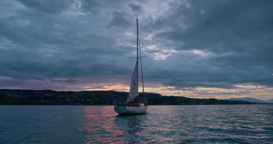 Boat sailing on the water off the coast under a cloudy sky at dusk