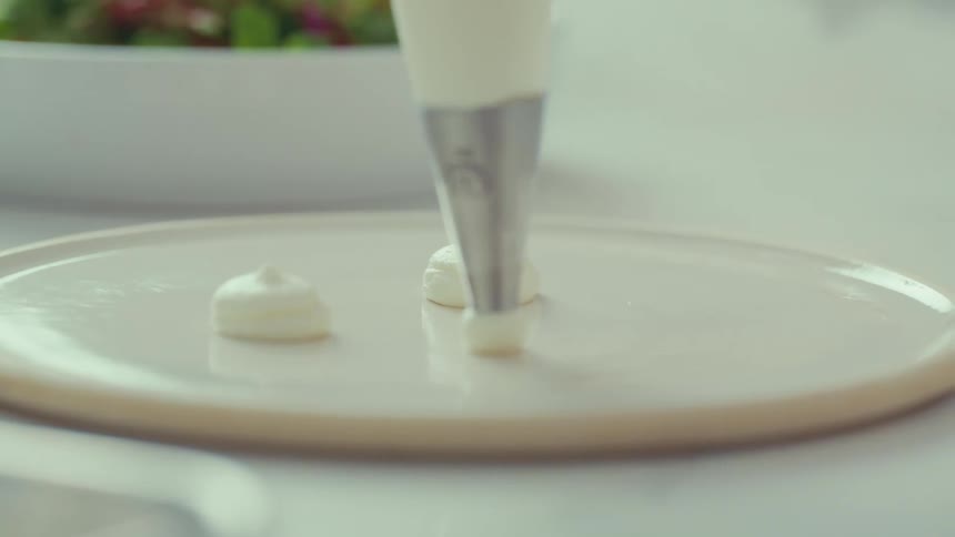 A frosting tip drops icing onto a surface