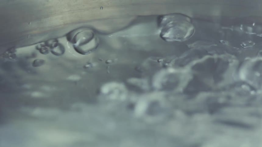 Water boiling in a pot with bubbles rising to the surface