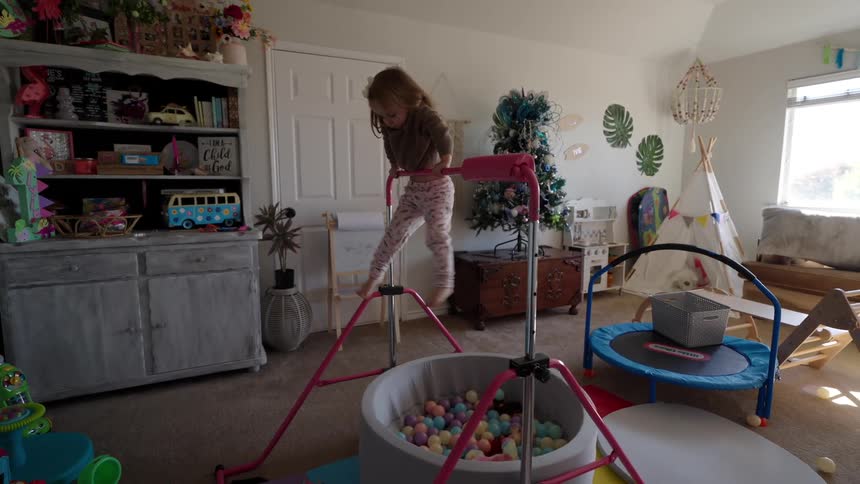 Little blonde girl playing hanging on a toy in a room