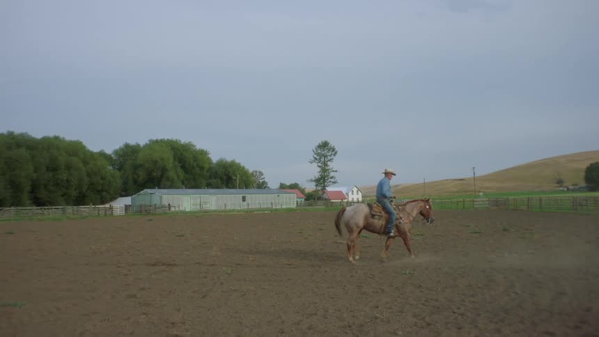 A man is horse back riding on the ranch