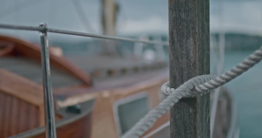 Hand holding a rope to a piece of wood