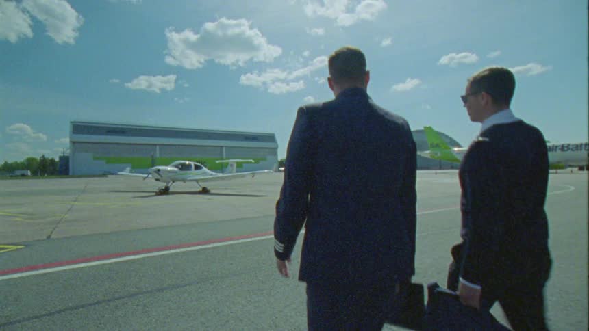 Two men are walking towards an airplane on the runway