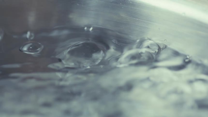A close up of water boiling inside a metal pan