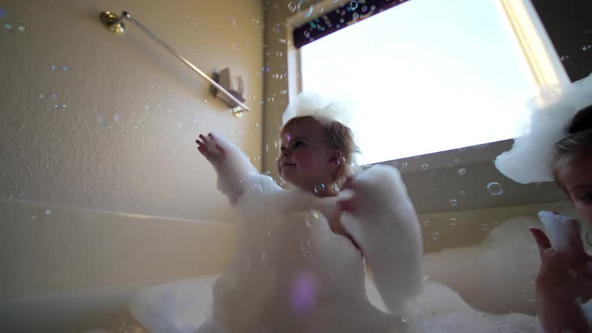 Two girls play in the bubble bath