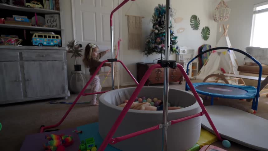 Sisters play in a playroom filled with trampolines ball pits other toys and a tent