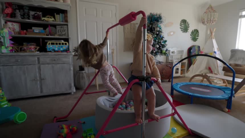 Sisters play in a playroom filled with trampolines ball pits other toys and a tent