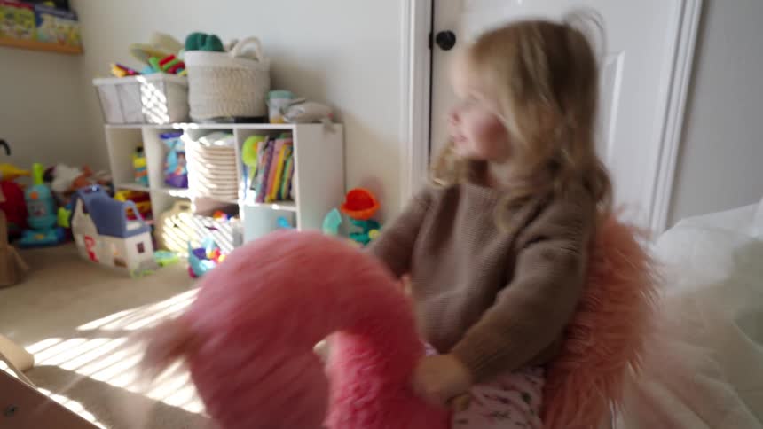 Little girl riding a stuffed toy and having fun in her room