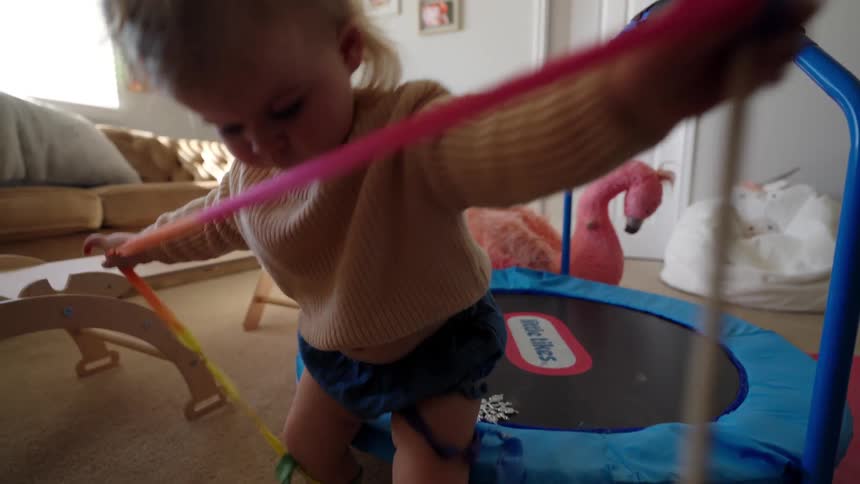 A girl playing with a colorful ribbon wand in her bedroom