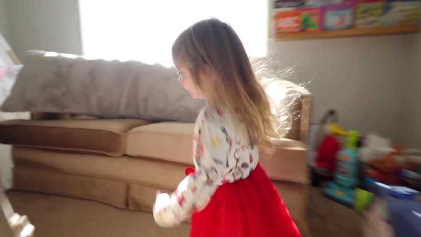 Little girl running around her room full of toys