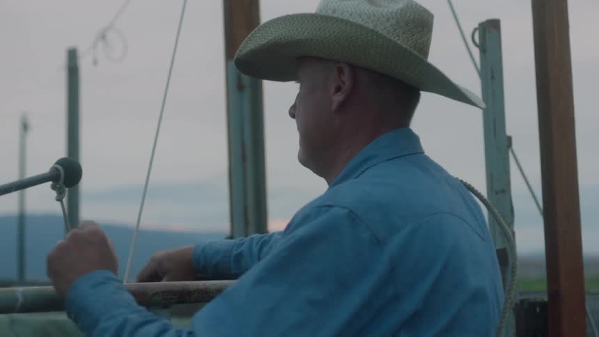Cowboy in hat leaning his arms on a railing