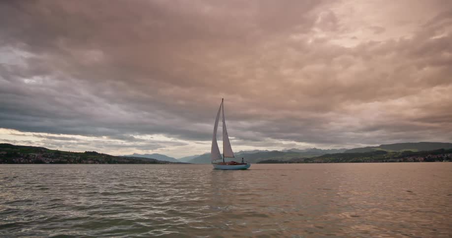Sailboat sailing in calm waters under cloudy skies
